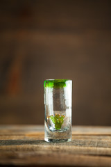 Squeezing lime into shot of tequila. Selective focus. Blurred background.