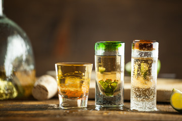 Shot glass of tequila on wood table. Selective focus. Blurred background.