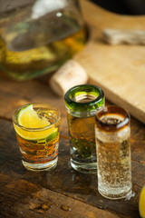 Shot glass of tequila on wood table. Selective focus. Blurred background.