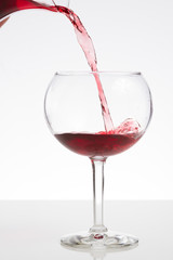 Red wine pouring into a wineglass with copy space