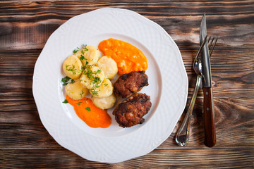 Meat cutlets and potatoes with pumpkin sauce on a wooden backgro