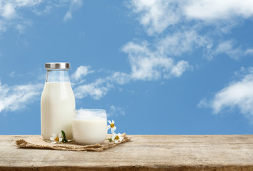 A bottle of rustic milk and glass of milk on a wooden table on a