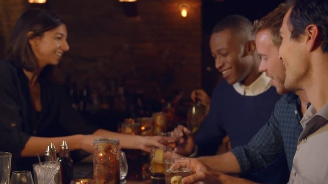 Male Friends Enjoying Night Out At Cocktail Bar, Slow Motion