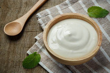 Greek yogurt in a wooden bowl with spoons on wooden background