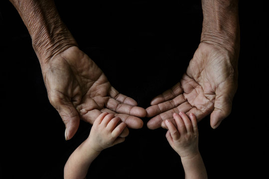 Hand of a young baby touching old hand of the elderly (Soft focu