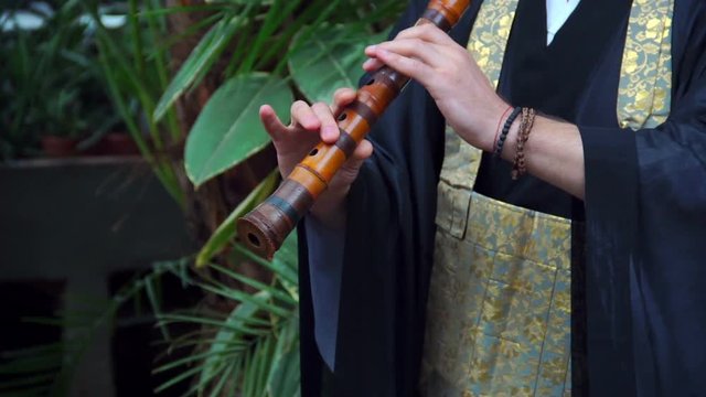 Japanese musician plays on flute in the park. Fue made of bamboo
