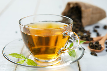 Warm cup of tea and leaves tea on white wooden