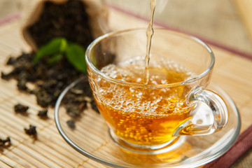 Cup of tea and leaves tea on wooden placemat