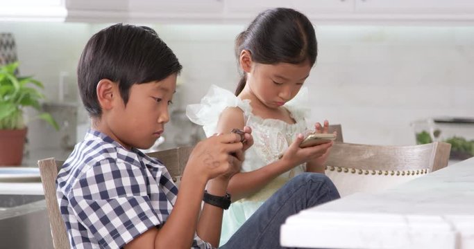 Asian Children Playing Games On Mobile Devices 