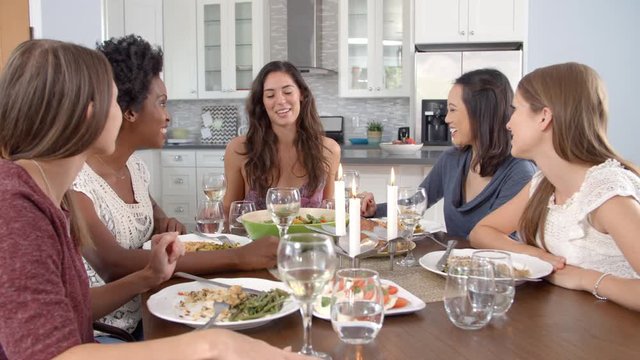 Female friends make a toast and eat at a table, slow motion