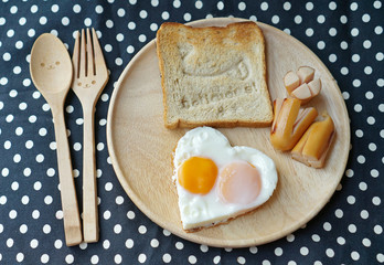 Breakfast consist of fried egg in shape of heart and happy bread