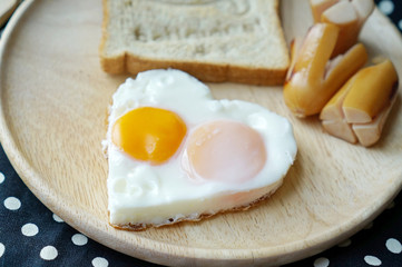 Breakfast consist of fried egg in shape of heart and sausages. C
