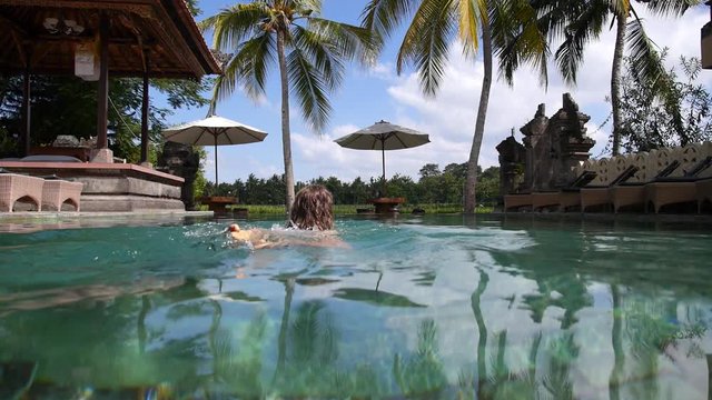 Woman Swimming in Pool in Tropical Resort on Vacation.