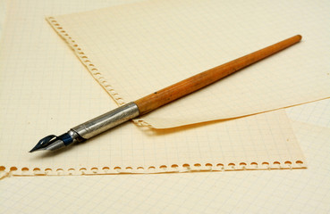 Old ink pen on background with sheets of paper