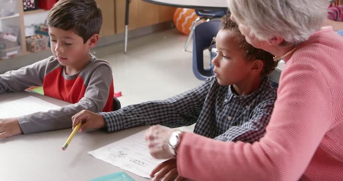 Senior teacher with young schoolboys in class, side view