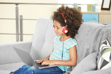Cute African girl with laptop on couch