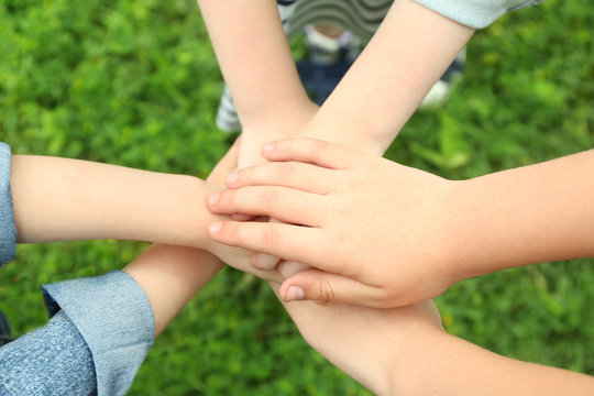 Children holding hands together on grass background