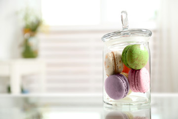 Colorful macaroons in glass jar on table