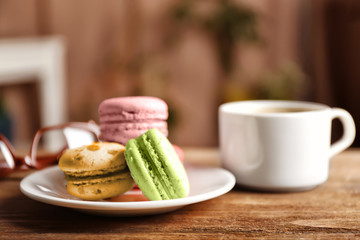 Heap of tasty macaroons in white plate on wooden table