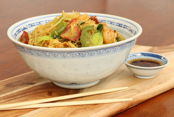 asian noodles with chopsticks and dipping sauce in a blue and white bowl