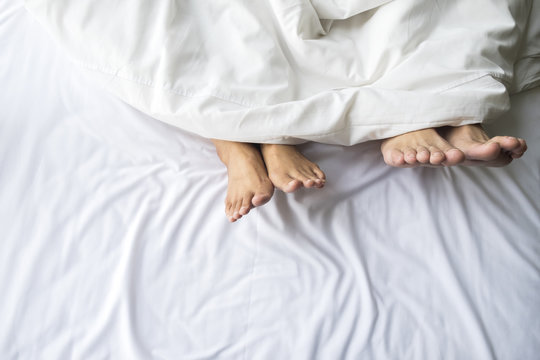 Feet of couple in comfortable bed.