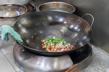 Chef in restaurant kitchen at stove with pan
