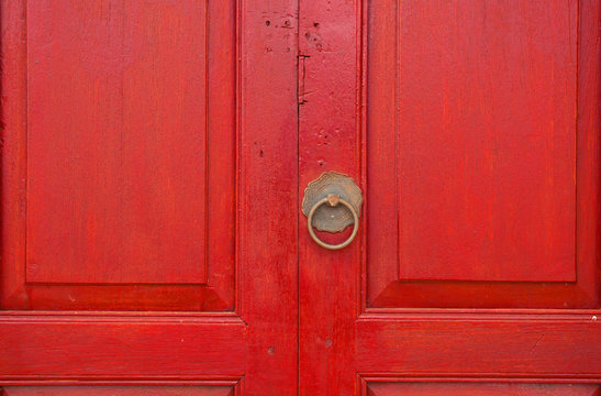 Brass door handle and knocker in chinese style on a red wooden d