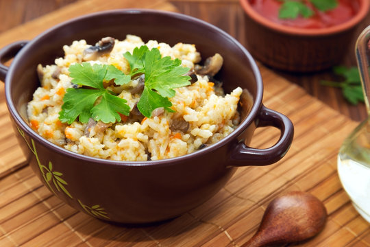 Rice with mushrooms and carrot or pilaf on wooden rustic table.