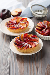 Homemade Tartlets with plum on rustic wooden table, selective focus