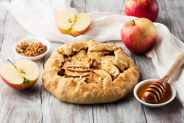 Homemade crostata with ripe apples and honey on rustic white table, selective focus