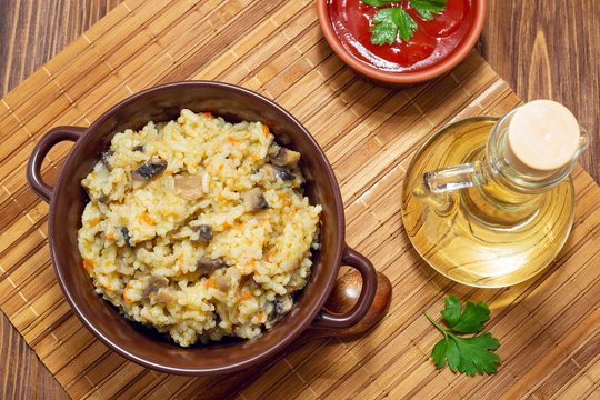 Rice with mushrooms and carrot on wooden rustic table. Olive oil