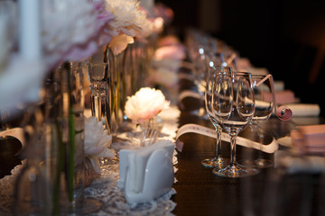 Fototapeta na wymiar Banquet table covered in, glasses and plates, forks and knives, napkins and buttons for a luxurious celebration in anticipation of guests, luxury festive table. 