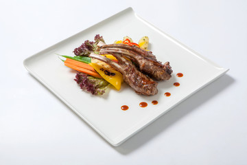 Pork ribs grilled with roasted vegetables and boiled potatoes on white plate