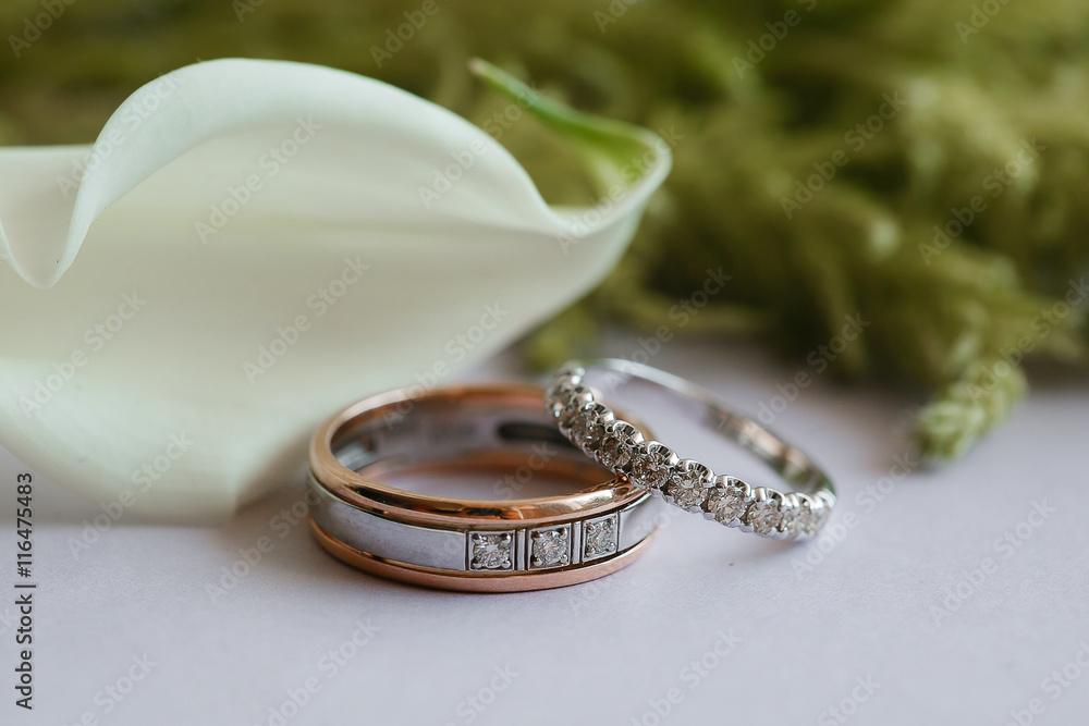 Wall mural wedding rings on table with calla lilies and greens