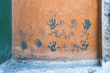 Prints of children's hands on the orange wall.
