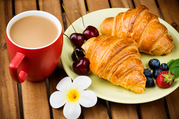 Cup of coffee and croissants on wooden background