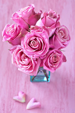 Beautiful fresh roses flowers in a vase on a pink background.