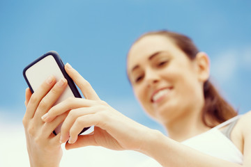 Female runner with her mobile smart phone standing outdoors