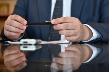 Businessman holding a pen between his hands 
