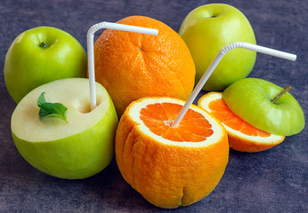 Juicy apples and oranges with tubes for a cocktail. Drink the ju