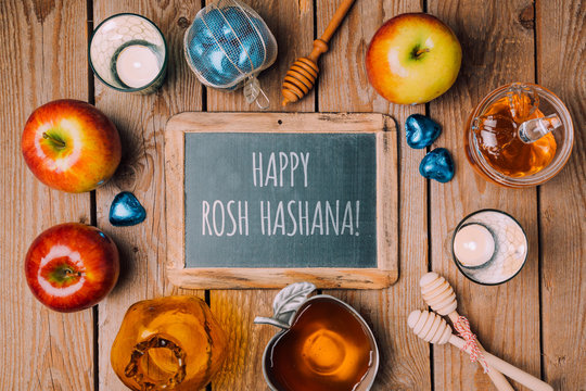 Jewish holiday Rosh Hashana background with chalkboard, honey jar and apple on wooden table. View from above. Flat lay