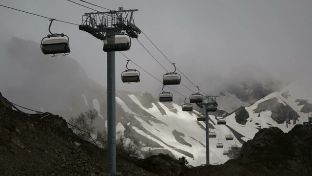 Cableway with open seats in mountains in cloudy weather
