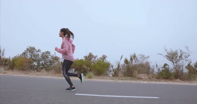 Female runner exercising on countryside road in morning. Fitness woman running outdoors.
