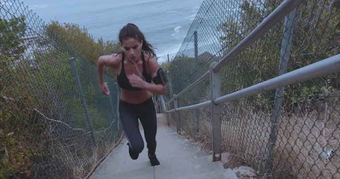 Outdoor shot of fit young woman running up stairs. Female athlete climbing up the steps.
