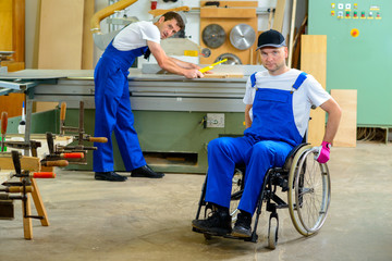 Fototapeta na wymiar worker in wheelchair in a carpenter's workshop with his colleagu