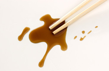 Soy sauce and chopsticks on white background