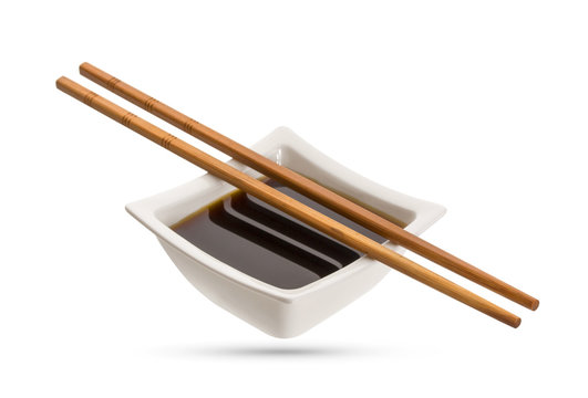 Bowl of soy sauce and chopsticks isolated on white background