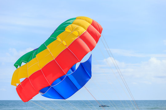 Parasailing, beach umbrella on sky background