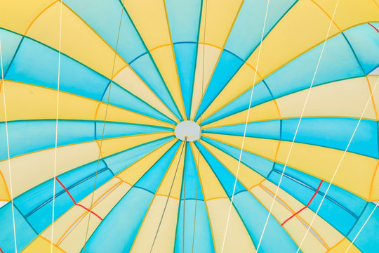 Parasailing, beach umbrella on sky background