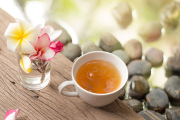 hot tea in white cup with flowers on wooden pebble stone water b